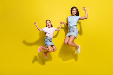 Photo of two girls sisters jumping with raise fists up enjoy kid children sale discounts isolated over bright color background