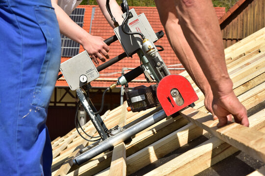 Die Dachlatten eines Steildachs werden vom Dachdecker mit dem Einlattger&auml;t / Einlattblitz mit Kapps&auml;ge halbautomatisch verlegt