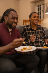 Mid adult couple eating meal in living room