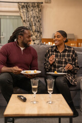 Mid adult couple eating meal in living room