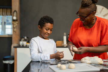 Fototapeta na wymiar Boy with grandmother preparing dough in kitchen