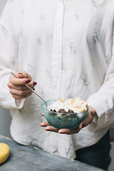 Woman eating healthy food for breakfast, cereal, granola, muesli, oatmeal with banana, dark chocolate and yogurt in a bowl