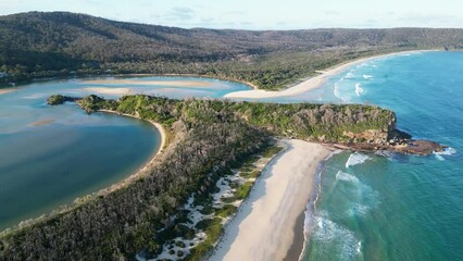 Aerial of the green headland surrounded by the calm ocean in New South Wales, Australia