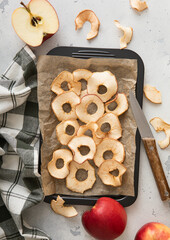 Sweet dried apple rings on baking tray with knife and kitchen towel.Macro.