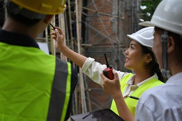 Close-up of a female engineer pointing at construction building, meeting of a worker team, Quality...