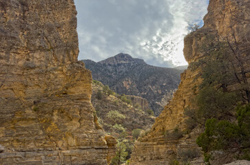 Naklejka premium A cloudy sky landscape over the desert in Texas looking through a canyon and mountains in Guadalupe Mountains National Park USA.