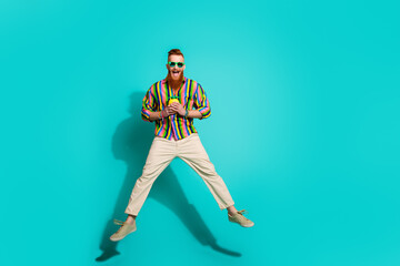 Full body length size photo of jumping young macho with red hair hold yellow pineapple cup for juice isolated on cyan color background