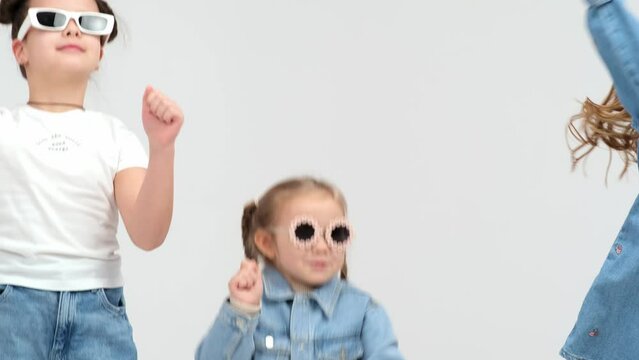 A group of small children dancing on a white background. The concept of stylish clothing, entertainment and modern relaxation.