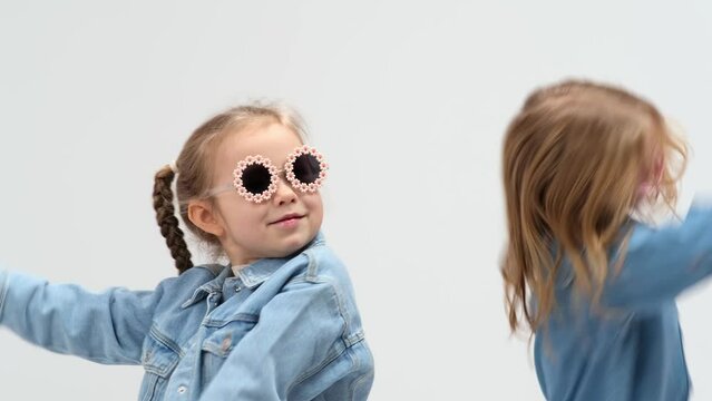 A group of small children dancing on a white background. The concept of stylish clothing, entertainment and modern relaxation.