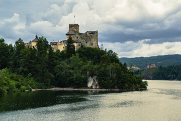 Fototapeta na wymiar Niedzica Castle located in the Pieniny Mountains with the Czorsztyn Castle in the background at Czorsztyn Lake on a cloudy day.