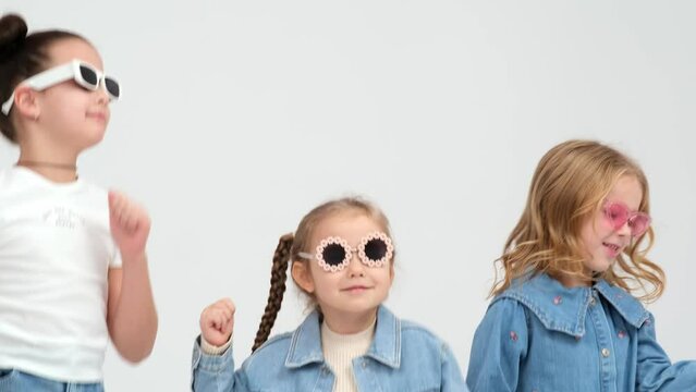 A group of small children dancing on a white background. The concept of stylish clothing, entertainment and modern relaxation.