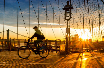 Bicyclist on Brooklyn Bridge during sunrise in New York. USA