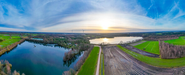 This panoramic aerial photograph captures a breathtaking view of a lakeside scene at sunset. The...
