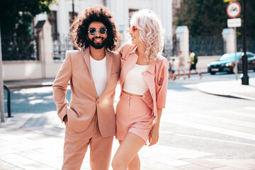 Beautiful fashion woman and her handsome elegant boyfriend in beige suit. Sexy blond model in summer suit clothes. Fashionable smiling couple posing in street Europe. Brutal man and female outdoors