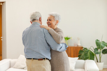 Keep moving. Romantic senior mature couple dancing to music together at home. Happy smiling family retired man woman husband wife having fun enjoying time together. Family moment love care