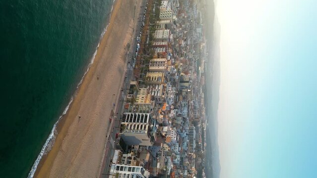 Beautiful gold sunset over famous city Lloret del Mar. Travel destination in Spain and one of the most famous beaches from Catalonia. Drone tracking left. Panoramic view. Vertical footage