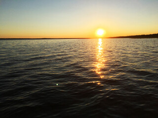 Obraz premium Evening lake with waves against sunset background