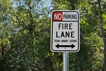 Fire Lane and no parking sign closeup isolated with a backdrop of tree canopy and copy space.