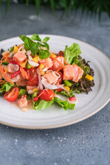 Tasty and fresh salad with raw salmon, greens, tomato, pepper, onion, carrot, olive oil.