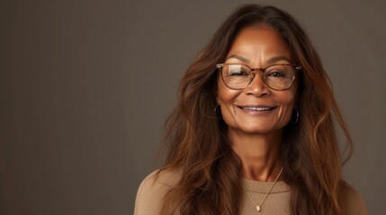Woman with long brown hair wearing glasses and a beige sweater smiling at the camera.