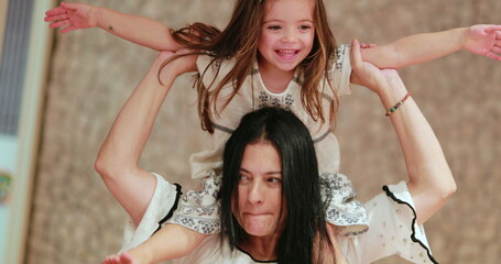 Happy grand-daughter clapping hands seated on top of grand-mother shoulders