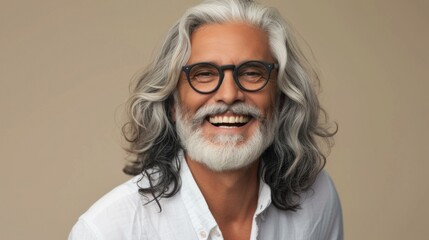 Smiling man with gray beard and hair wearing glasses in white shirt against beige background.