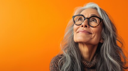 A smiling elderly woman with gray hair wearing glasses and a brown turtleneck. - 731846767