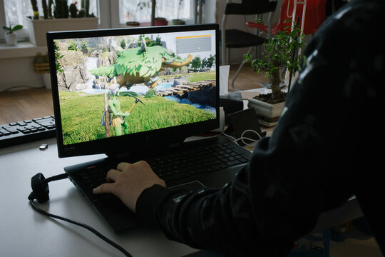 BERLIN, GERMANY - FEB 9, 2024: Hands of teenager playing Palworld game released earlier this year on a Windows laptop at home