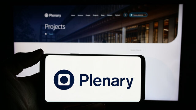 Stuttgart, Germany - 02-07-2023: Person holding cellphone with logo of Australian infrastructure investment company Plenary Group in front of webpage. Focus on phone display.