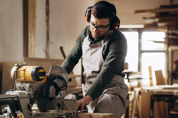 Carpenter working with wood and saw in the manufacturing industry - obrazy, fototapety, plakaty