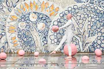 Young hairless girl ballerina with alopecia in white futuristic suit dancing outdoor and jumps with...