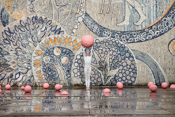 Young hairless girl with alopecia in white futuristic suit dancing outdoor smoothly holding pink...