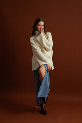 Fashionable happy smiling woman wearing oversized white turtleneck sweater, maxi blue denim skirt,...