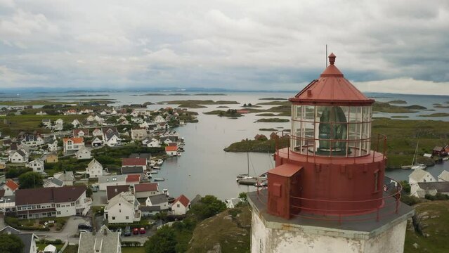 Cinematic Kvits&oslash;y Island, white with red top Lighthouse slow rise, revealing harbour boats and village Ytstebohamn in the background North Sea cloudy skyes moving in over this isolated Island.
