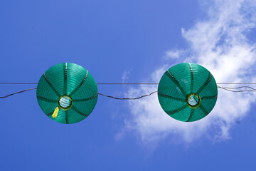 A collection of red paper lanterns hanging against a clear blue sky. - Powered by Adobe