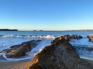 Sunrise on a beach. Waves curling on the rocky shore.  Dawn on the beach.Large rocks forming a channel in the water. Beach at sunset. Ocean view at low tide.