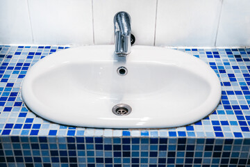 Stylish white sink with blue and white mosaic tiles in a modern bathroom