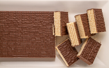 Several sweet chocolate wafers on a ceramic dish, macro, top view.