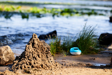 Obraz premium River bank. Children's plastic boat. Sand castle. 