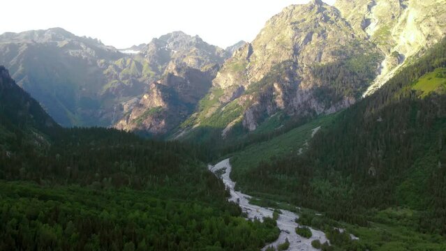 Aerial view of the Dolra River, and Ushbi waterfall at distance. forest and high Caucasian mountains. way to Ushba mount, a hiking trail, a tourist route. Svaneti, Georgia