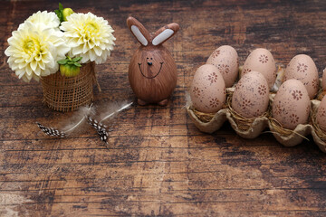 Dekoration mit Ostereiern, Blumen und einer Osterhasenfigur auf schäbigem Holzbrett mit Platz für...