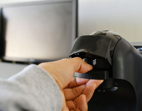 Colocaci&oacute;n de una capsula para hacer caf&eacute; en una maquina autom&aacute;tica. Espacio para texto al lado izquierdo.