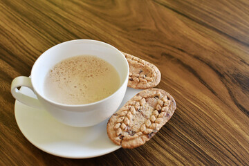 Café con leche y galletas saludables en una mesa de madera, espacio para texto al lado derecho.