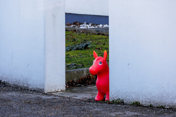 A red toy horse stands in the passageway in a white wall on a street in Augsburg