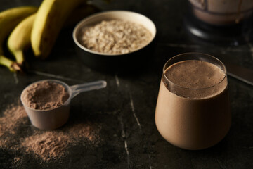 Chocolate Protein Power Cocktail with Ripe Bananas, Whole Oats, and Creamy Milk in a Modern Glass, Ideal for Post-Workout Recovery, Set Against a Dark, Textured Background