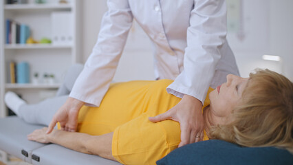 Fototapeta premium A trauma doctor assesses a senior woman's shoulder, focusing on injury treatment and rehabilitation