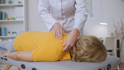 Close-up of a doctor's hands massaging a female patient's back, offering manual therapy treatment
