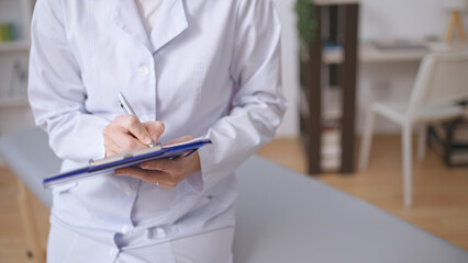 Close-up of a female doctor documenting symptoms in a patient's medical record for diagnostics