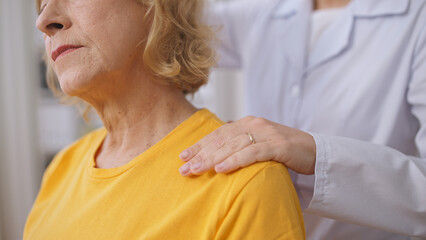 A female osteopath gently massages a senior patient's neck, practicing alternative medicine