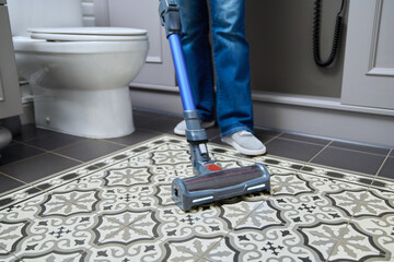 Vacuuming in the bathroom, woman doing cleaning